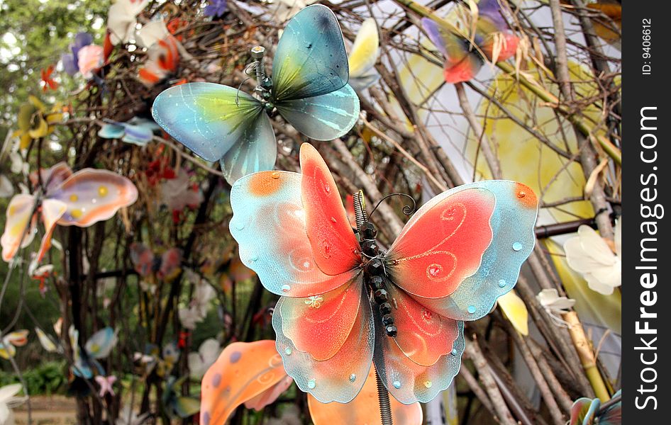 Some fake butterflies decorate an outdoor area in a garden. Some fake butterflies decorate an outdoor area in a garden.