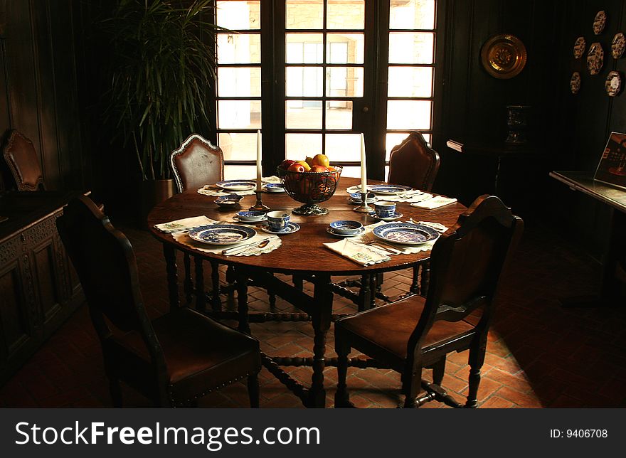 A dining table is decorated in old world style in a dimly lit room.