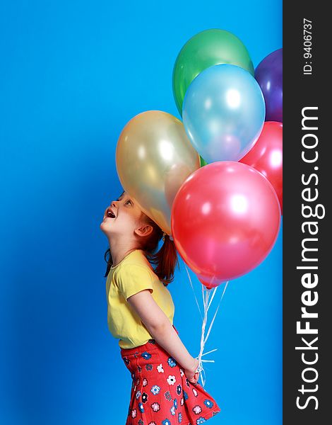 Little girl holding colorful balloons on a blue background. Little girl holding colorful balloons on a blue background