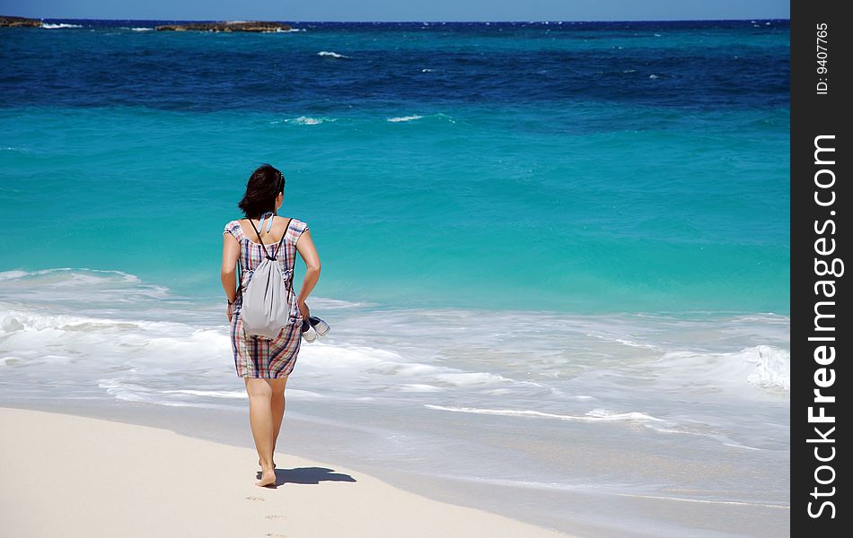 The girl walking on Paradise Island beach, The Bahamas.