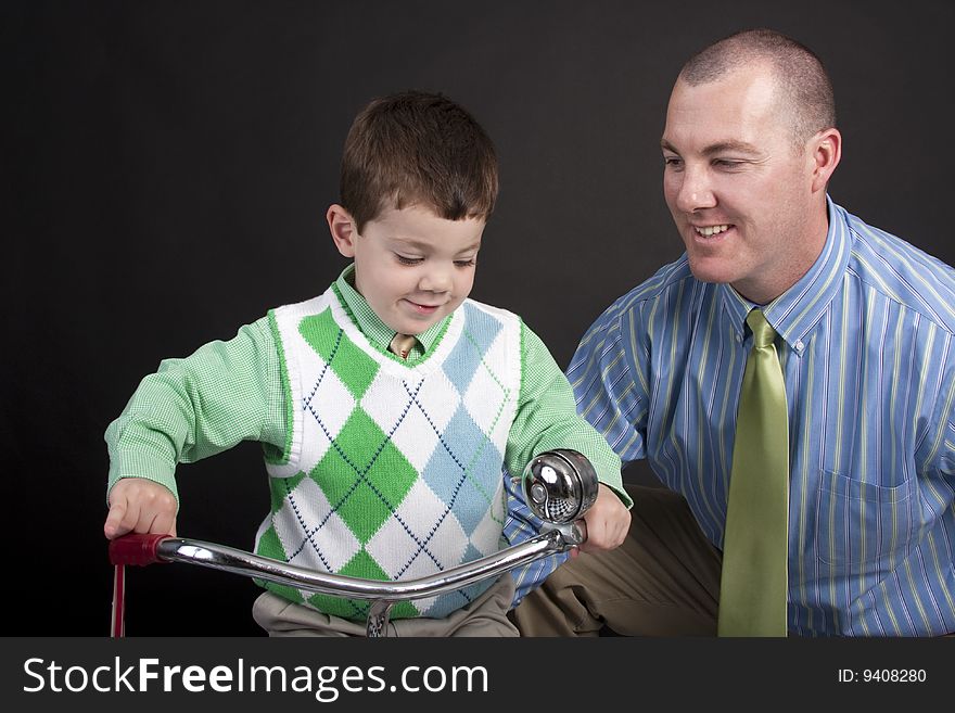 Proud father looking at young toddler son on a tricycle. Proud father looking at young toddler son on a tricycle