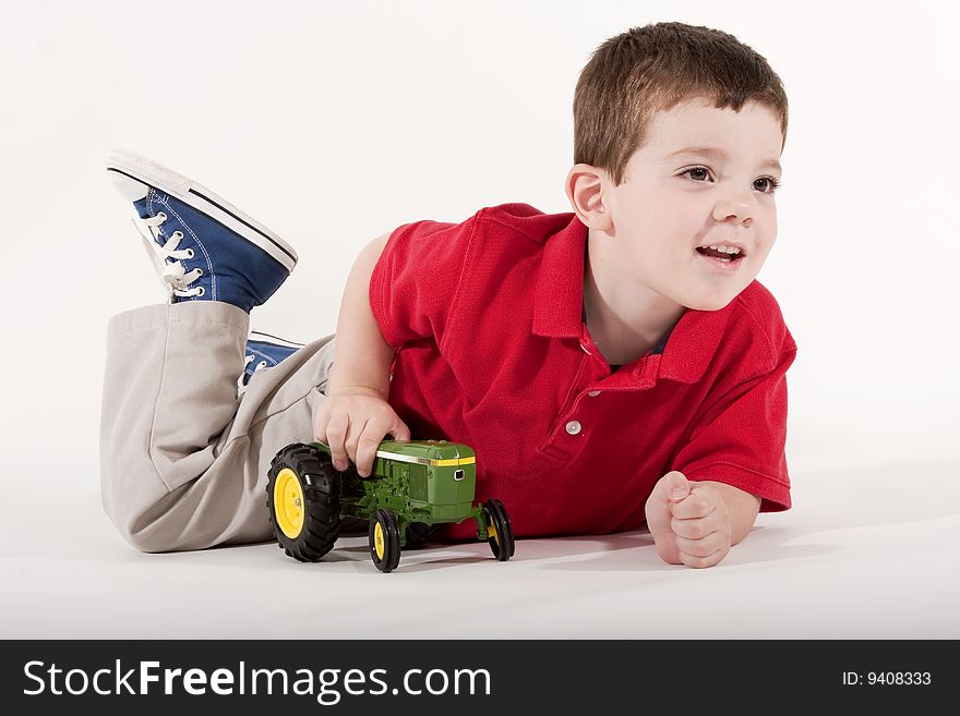 Young boy playing with a toy tractor on isolated background. Young boy playing with a toy tractor on isolated background