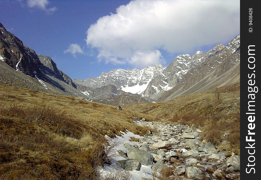 The valley in mountains, a stony channel of stream Muguvek, is in the distance visible a wall of rocky tops