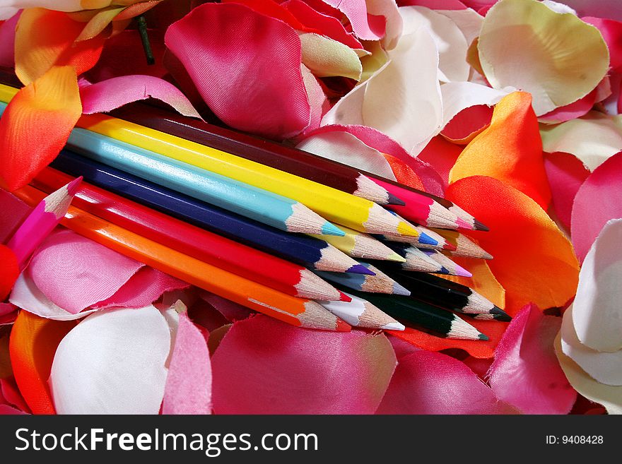 A bunch of colored pencils and some petals