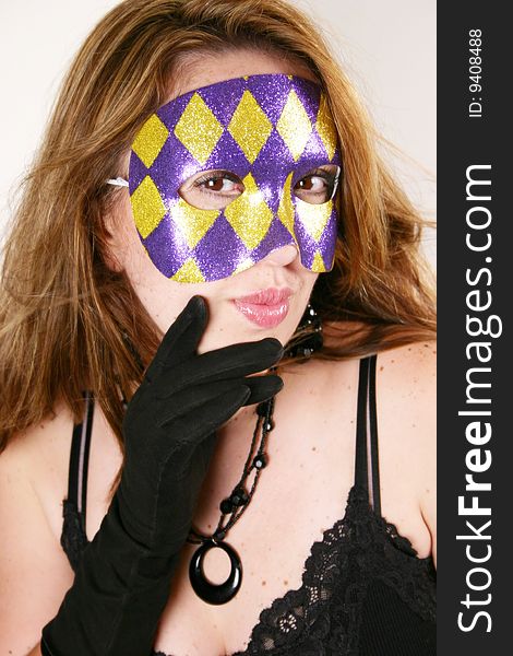 A woman wearing black gloves holds a purple and gold Domino mask over her face. A woman wearing black gloves holds a purple and gold Domino mask over her face