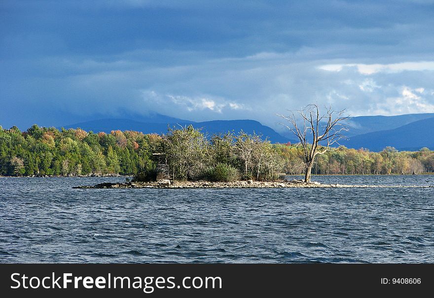 Small island in a lake with a storm in the distant mountains. Small island in a lake with a storm in the distant mountains