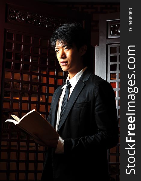 Asian man in business suit with book