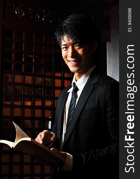 Asian man in business suit holding a book. Asian man in business suit holding a book.