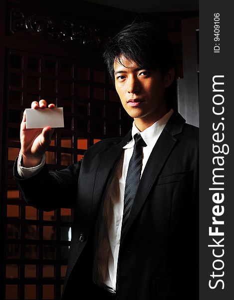 Asian man in business suit holding up a blank card. Asian man in business suit holding up a blank card