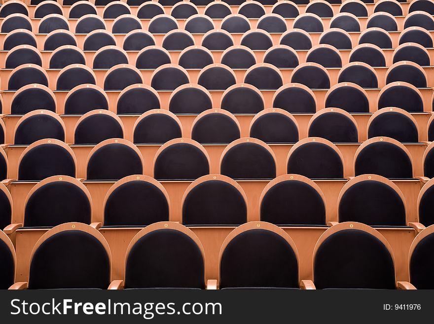 Close-up of empty cinema auditorium with line of wooden chairs.