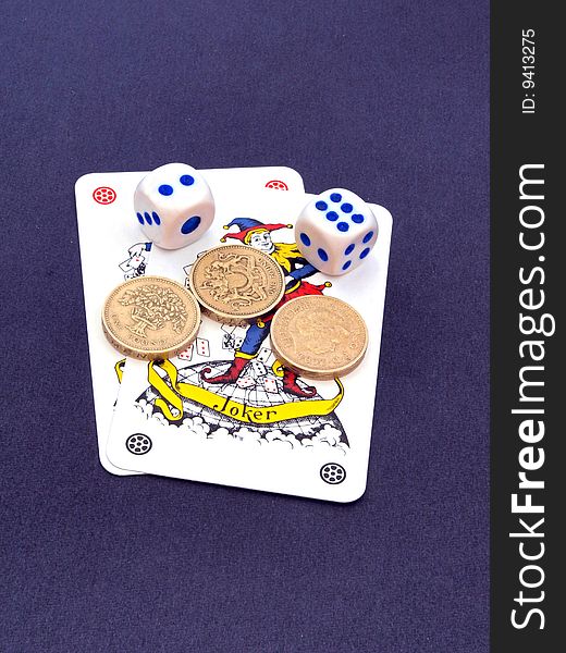 Concept of gambling showing coins, the joker playing cards and dice. Concept of gambling showing coins, the joker playing cards and dice.