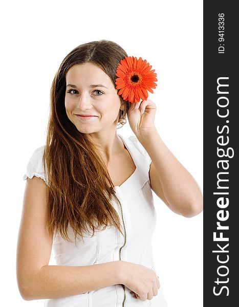 A smiling beautiful young woman in a white dress with a bright red flower near her face. A smiling beautiful young woman in a white dress with a bright red flower near her face
