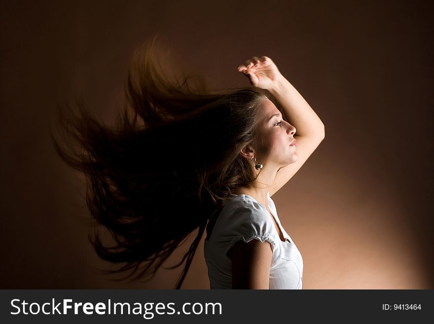 Fashion portrait of a young woman with hair lightly fluttering in the wind on a dark background. Fashion portrait of a young woman with hair lightly fluttering in the wind on a dark background