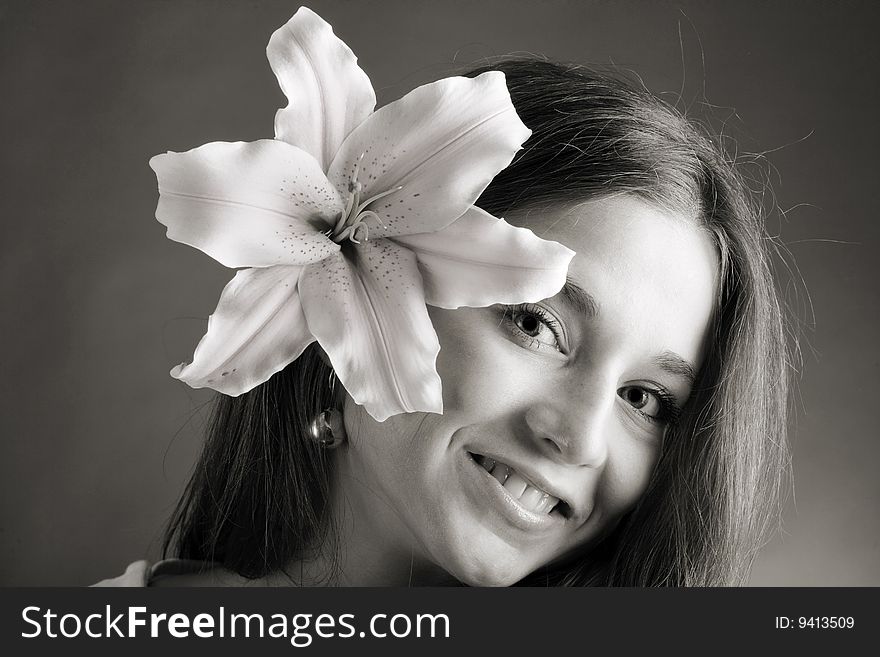 A pretty young woman with long hair posing with a lily nea rher face. A pretty young woman with long hair posing with a lily nea rher face