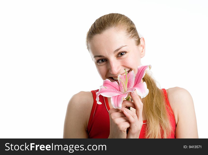 A smiling nice girl in red posing with a pink lily near her face on a white background. A smiling nice girl in red posing with a pink lily near her face on a white background