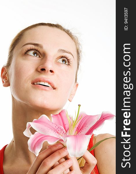 A portrait of a nice blond girl in red with a pink lily near her face on a white background. A portrait of a nice blond girl in red with a pink lily near her face on a white background