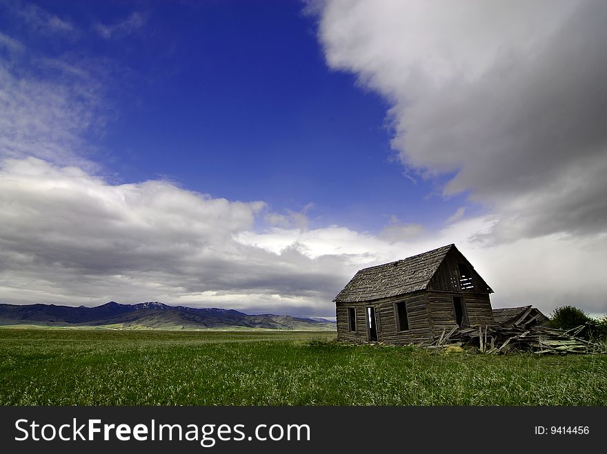 Old cabin in field with storm clouds in sky. Old cabin in field with storm clouds in sky