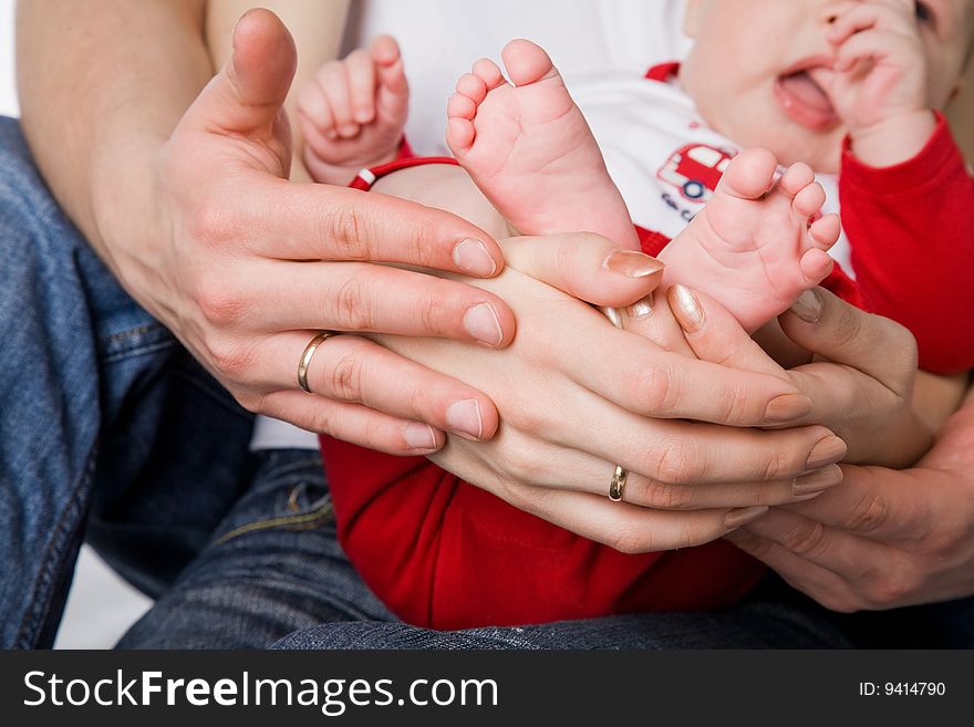 Mother and father holding litttle legs of their child studio shot. Mother and father holding litttle legs of their child studio shot