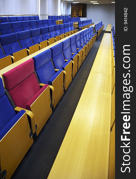 Red armchair among dark blue armchairs in a hall for holding conferences