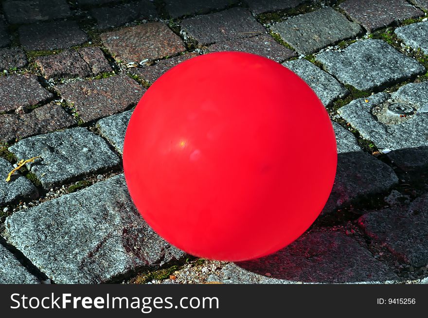 A red ballon on a cobbled street