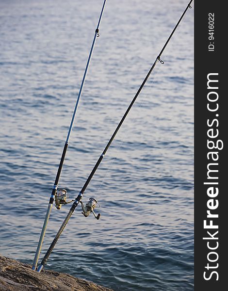 Two fishing rods cast into a blue calm sea.