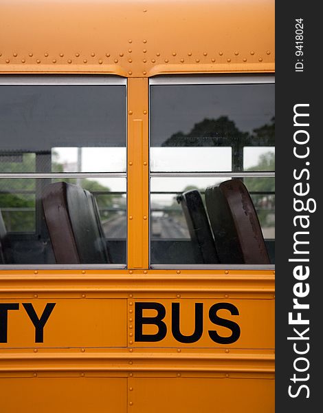 A detail of a school bus - windows and two rows of seats - with a view of a highway in the background