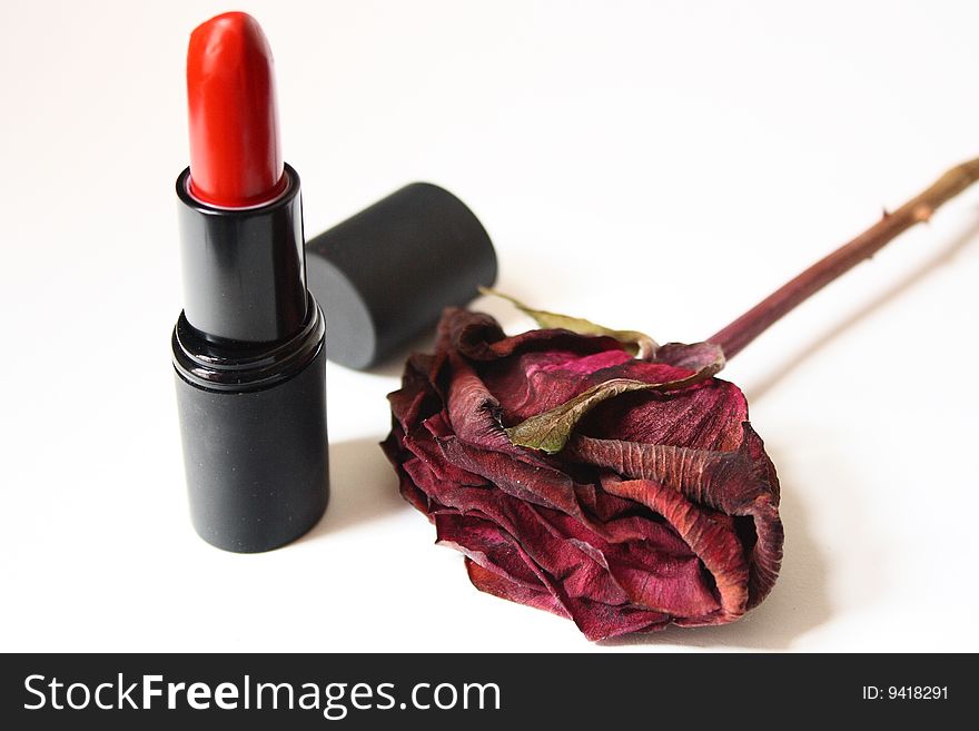 Red lipstick and a dried rose with white background. Red lipstick and a dried rose with white background