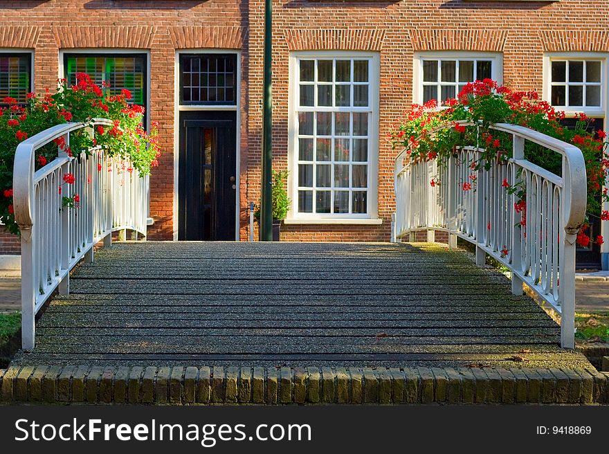 Old bridge railings that are decorated with boxes of flowers on a background of a typical Dutch house