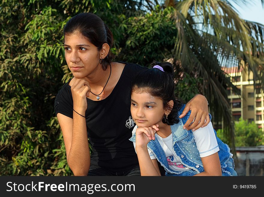 A small girl and her young sister engrossed in deep thoughts. A small girl and her young sister engrossed in deep thoughts.