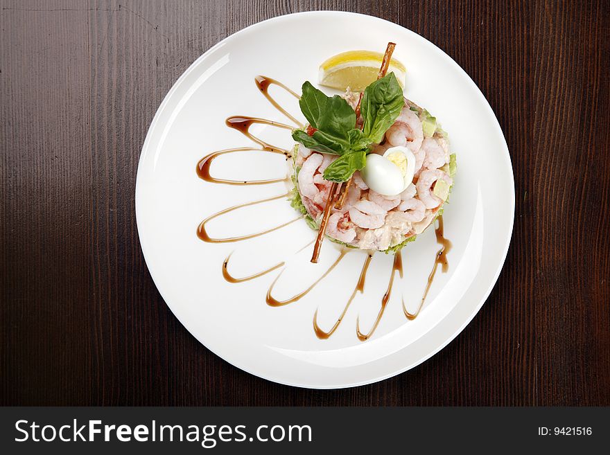 Plate with shrimp salad on brown table with clipping path
