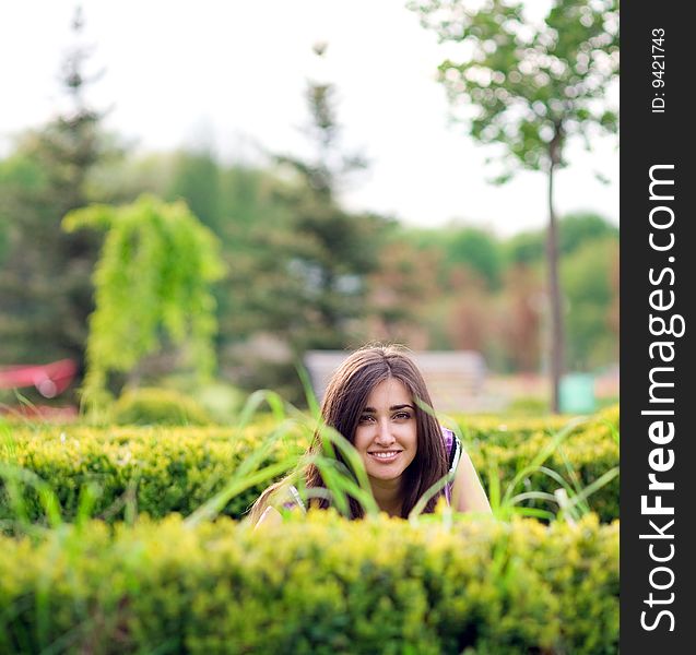 Young girl hiding over bush in park