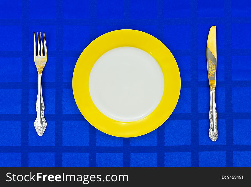 Plate, knife and fork on table cloth, food background