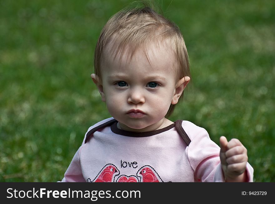 Frowning baby girl playing outdoors. Frowning baby girl playing outdoors