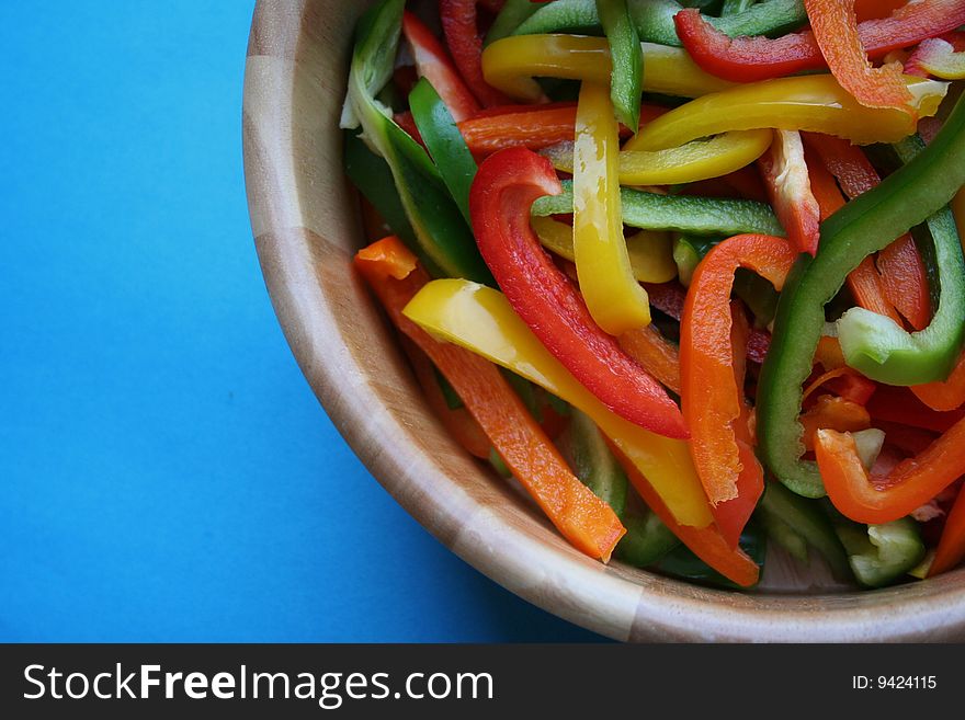 Red green orange and yellow peppers cut up inside a salad bowl. Red green orange and yellow peppers cut up inside a salad bowl