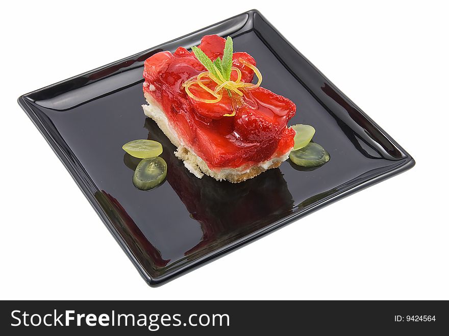 Cheesecake with strawberries on black plate isolated. Cheesecake with strawberries on black plate isolated