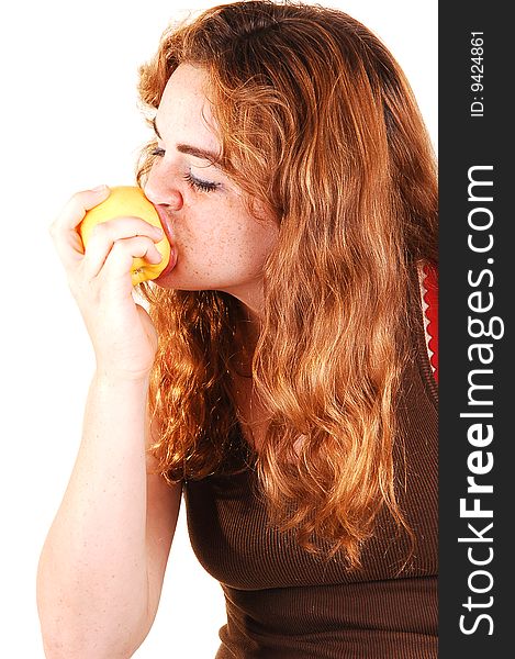 Pretty girl with long bright red hair eating an yellow apple and really enjoying the fruit. Pretty girl with long bright red hair eating an yellow apple and really enjoying the fruit.