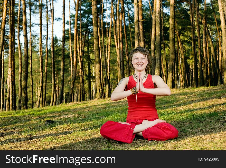 A young pretty woman sitting in lotos pose on the forest background