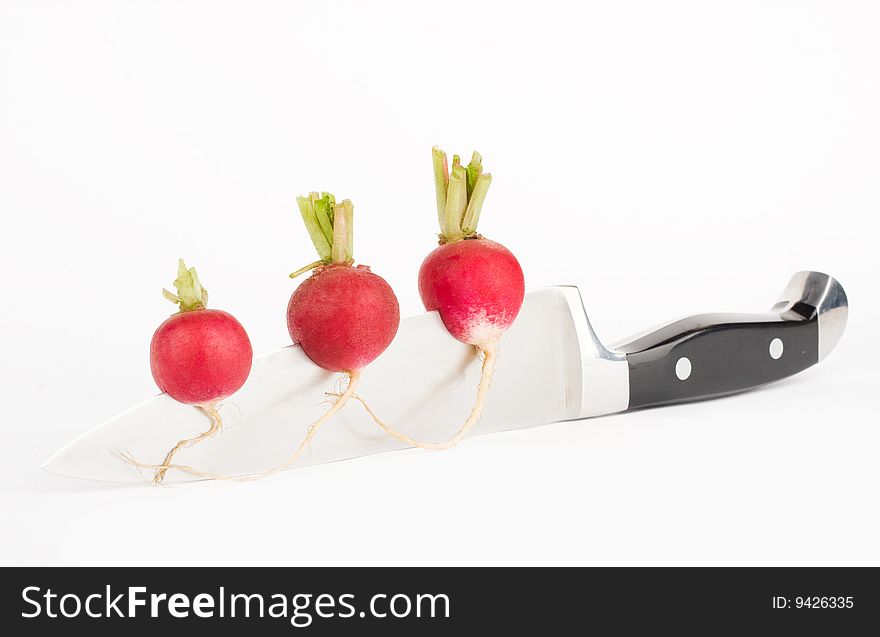 Three red radishes fixed on a knife  blade. Three red radishes fixed on a knife  blade
