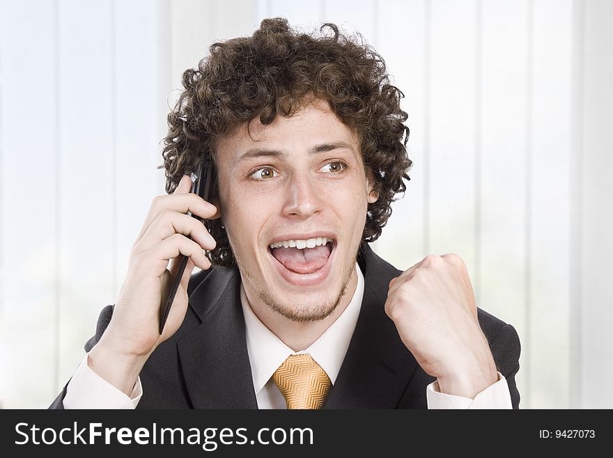Happy businessman with cellular phone in the office