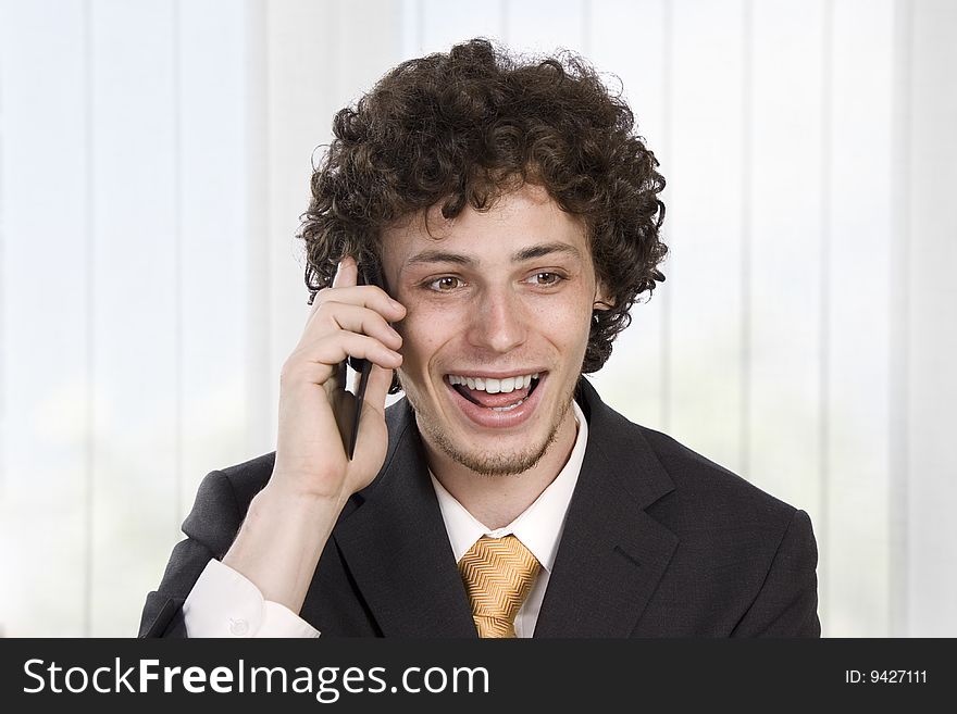 Happy gesturing business man with mobile phone in the office