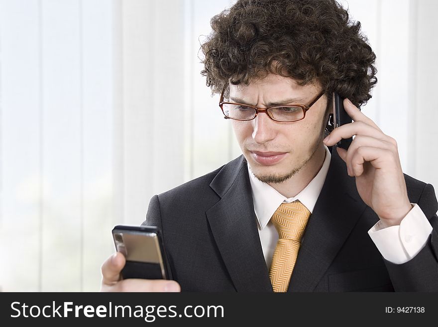 Troubled business man with two mobile phone in the office