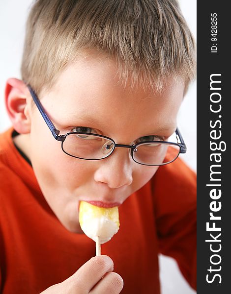 Boy eating yellow ice cream. Boy eating yellow ice cream.