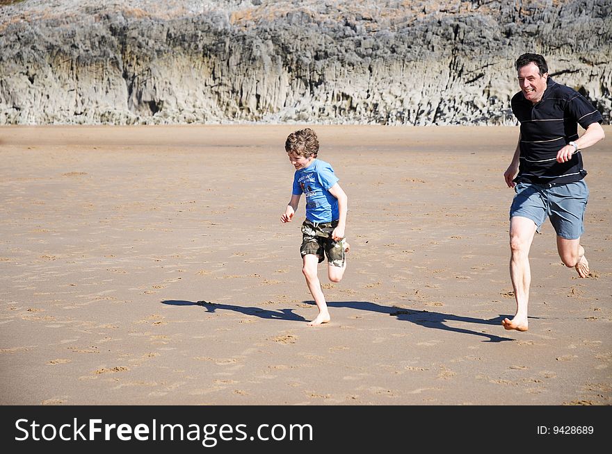 Father And Son Racing Along The Beach