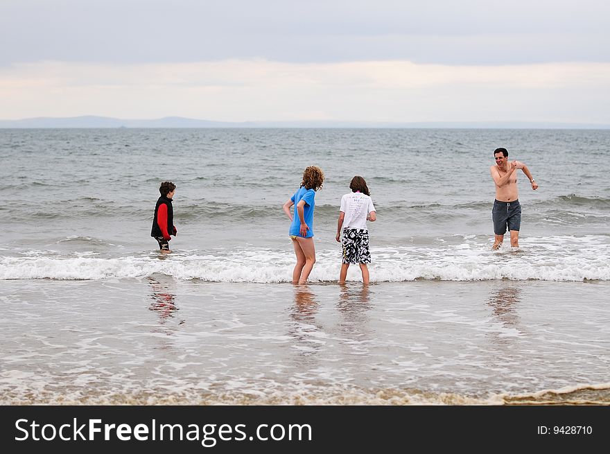Father And Children Wading In Cold Sea