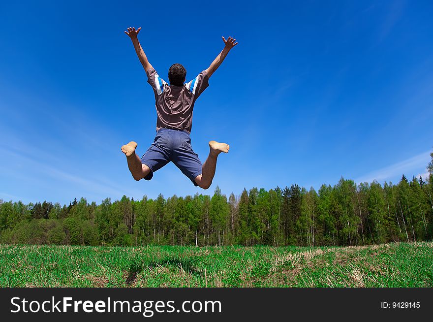 Man jumping on a green meadow with a beautifu  sky. Man jumping on a green meadow with a beautifu  sky
