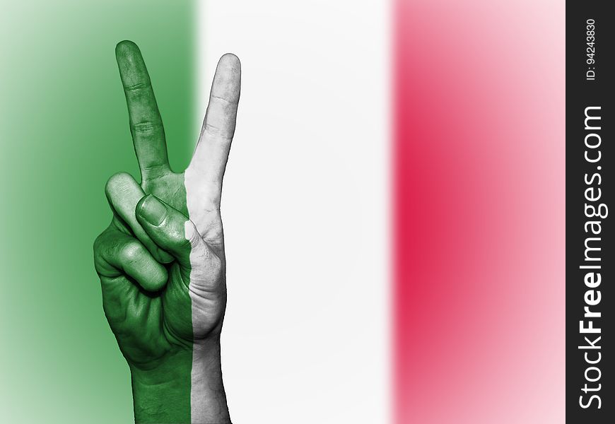 A hand showing the peace symbol and the Italian flag in the background. A hand showing the peace symbol and the Italian flag in the background.