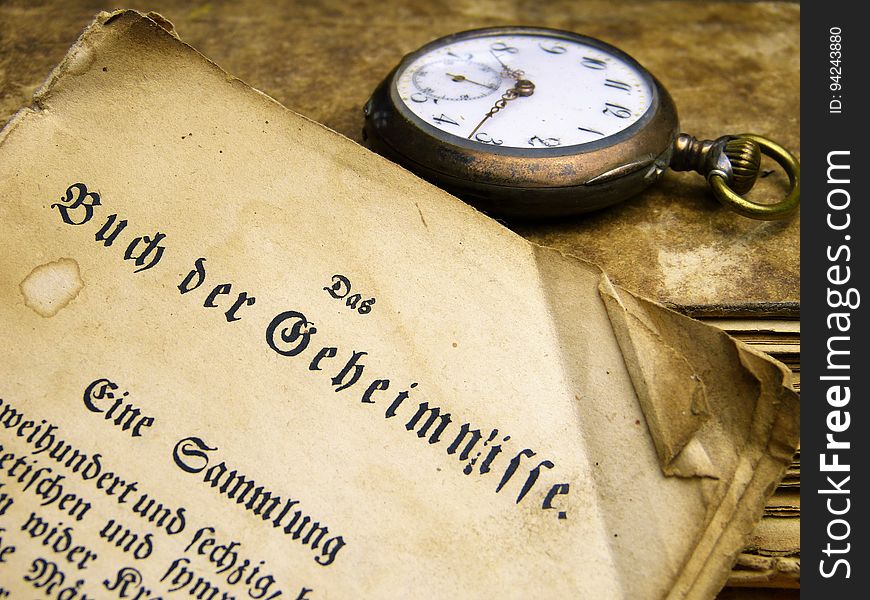 A close up of an old document and a watch. A close up of an old document and a watch.