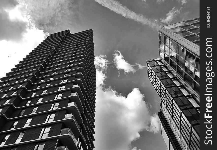 A low-angle view of city skyscrapers in black and white. A low-angle view of city skyscrapers in black and white.