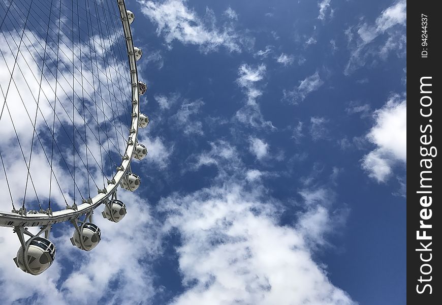 A white ferris wheel going around on a sunny day.