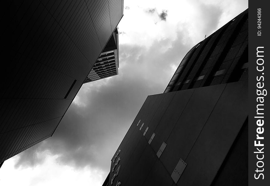 Architecture from an acute angle showing two high rise buildings (or skyscrapers) in low light, outlining some windows in the sides and producing an abstract background.